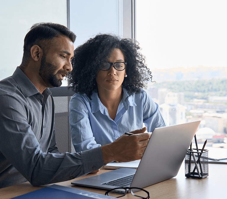 Two people in operations reviewing work on computer using GoCanvas solutions.