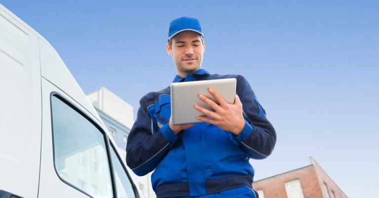 Man on tablet in front of a moving truck.